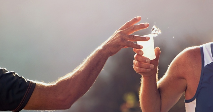 Runner getting passed a glass of water